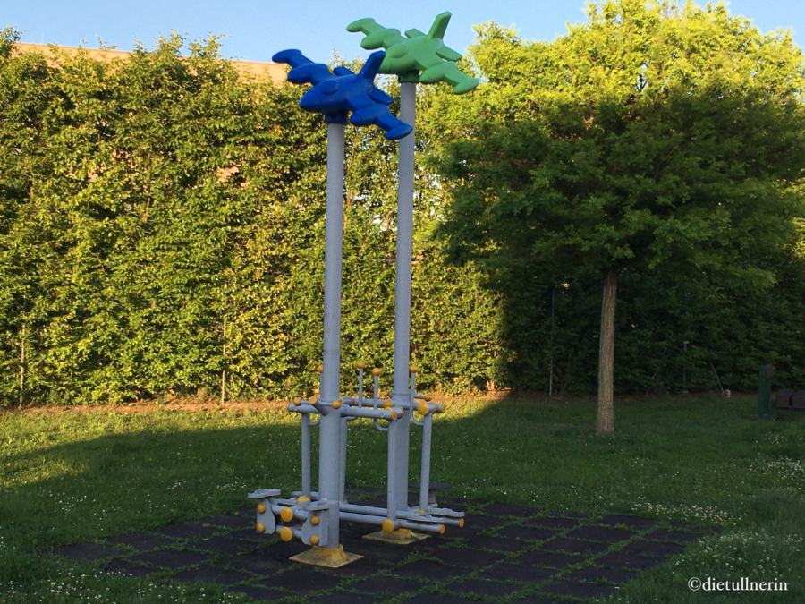 Fitnessgerät für Erwachsene mit blauem und grünem Kunststoff-Flieger am höchsten Punkt –inmitten einer Grünzone im Tullner Komponistenviertel