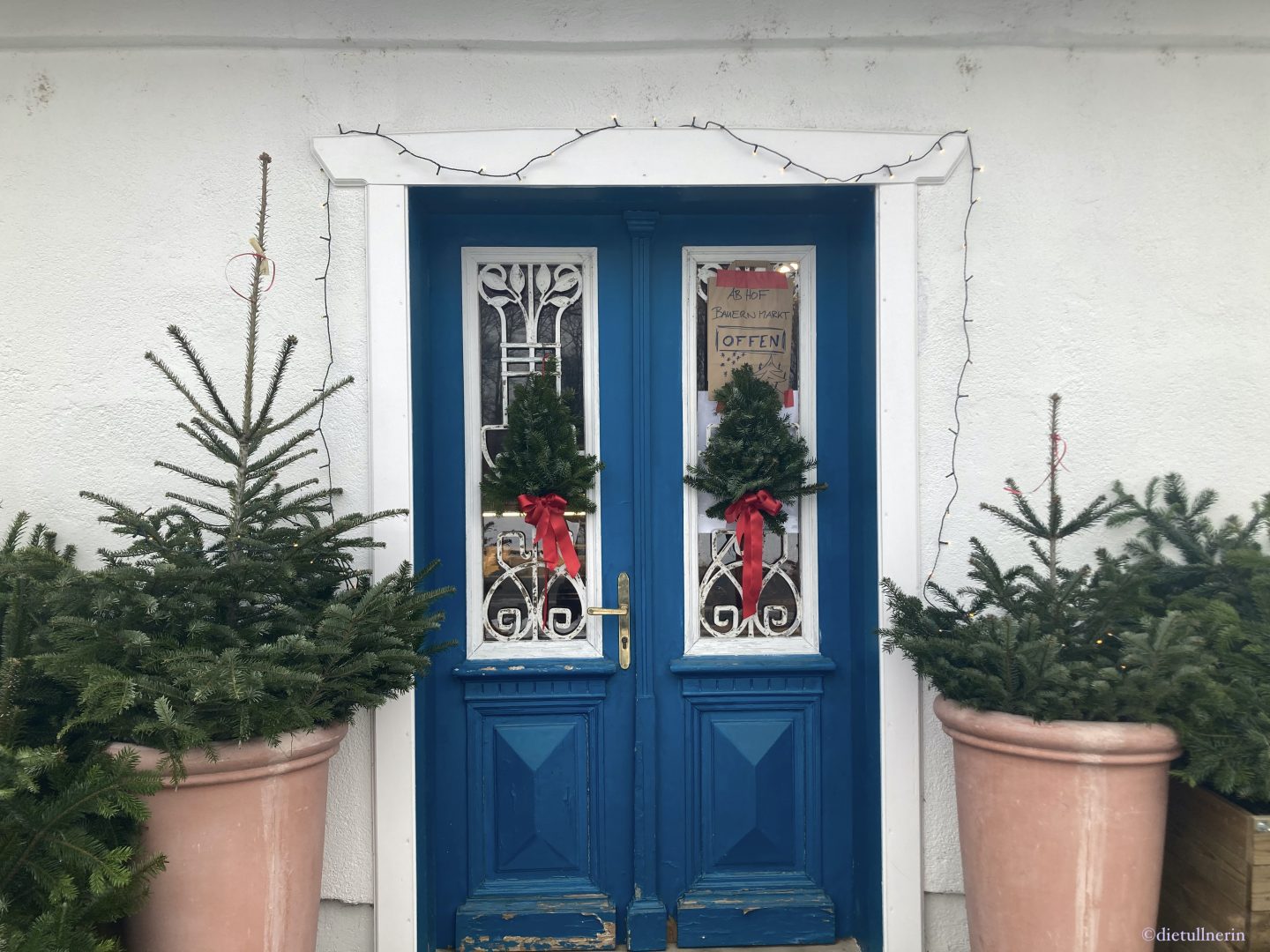 Blaue Eingangstür zu HuBees Hofladen weihnachtlich dekoriert