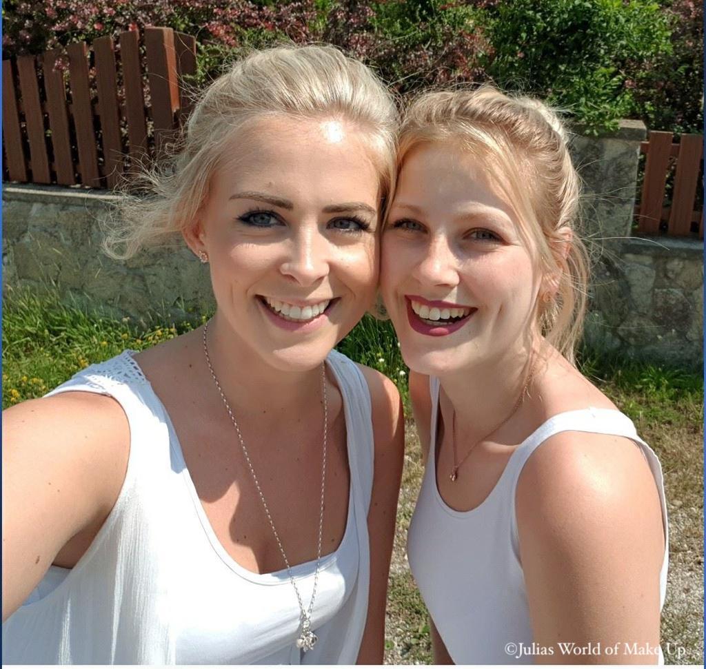 2 junge blonde Frauen in weißen T-Shirts, die herzlich für ein Selfie-Bild lachen