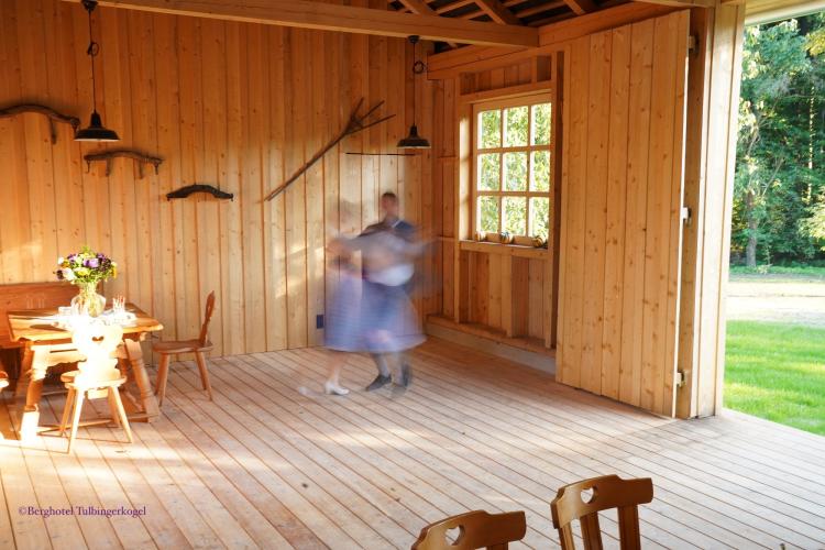 Holzstadel als Location für Feste jeder Art. Böden und Wände aus Holz. Das 9-teilige Fenster ist ebenfalls mit Holzrähmchen ausgestattet.  An den Wänden hängen traditionelle Arbeitsgeräte aus dem 19. Jahrhundert